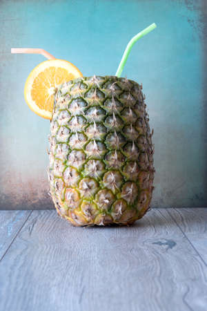 pineapple and oranges with straws close-up on wood on grungy blue  backgroundの写真素材