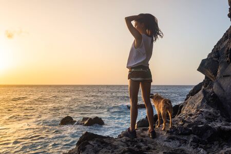 girl with her dog at sunset on the seaの写真素材
