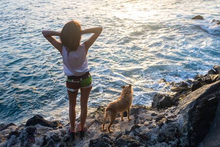 girl with her dog at sunset on the seaの写真素材