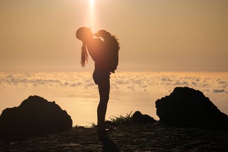 Silhouette of girl with puppy on sunsetの写真素材