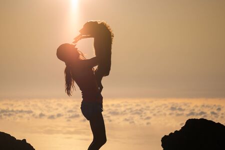Silhouette of girl with puppy on sunsetの写真素材