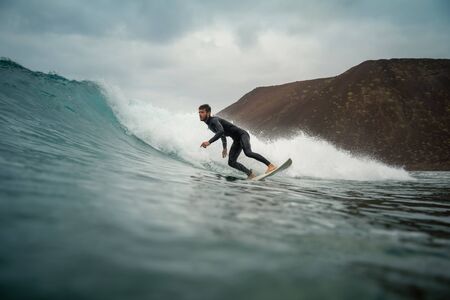 Surfer riding waves on the island of fuerteventura in the Atlantic Ocean, Canary Islandsの写真素材
