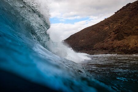 breaking wave with the tube and blue water with the clouds at the backgroundの写真素材