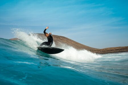 Surfer riding waves on the island of fuerteventura in the Atlantic Ocean, Canary Islandsの写真素材