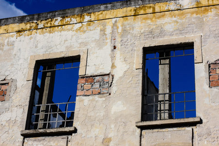falling apart building with iron bars in the windows showing blue sky in the background