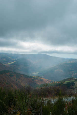 Mountain landscape with forests of green, red, orange and yellow colors that contrast the landscape. Beautiful views of nature with blue and gray skies.の写真素材