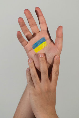 Colors of the Ukrainian flag painted on the palm of one hand as a symbol against the war they are...