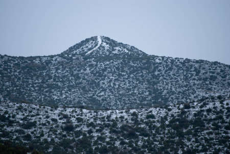 Snowy mountain with snow-filled roads on the ground and grass.の写真素材