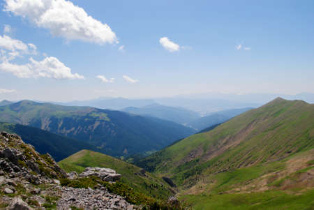 Mountainous landscape of long green mountain ranges with a clear blue sky with few clouds.の写真素材