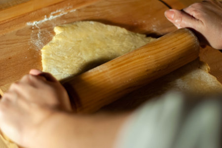 Baker's hands working the flour dough on a wooden boardの写真素材