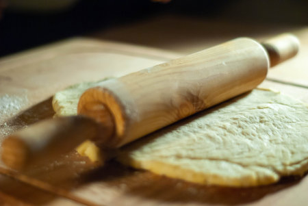 Baker's hands working the flour dough on a wooden board