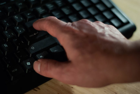 Hands typing on a computer keyboard with a mouse, close-up in front of the screen