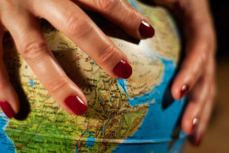 Hands of a woman holding a globe of the planet earth with marked places to travel on vacationの写真素材