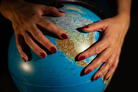 Hands of a woman holding a globe of the planet earth with marked places to travel on vacation