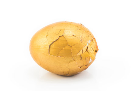 Broken gold egg on a white background.