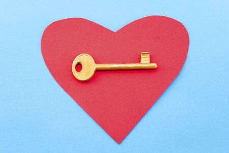 Red heart and a golden key on a blue background.の写真素材