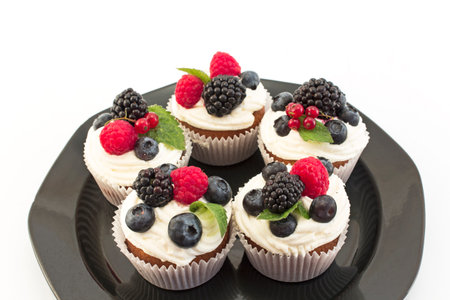 Elegant Cupcakes with Berries on the Black Plate.