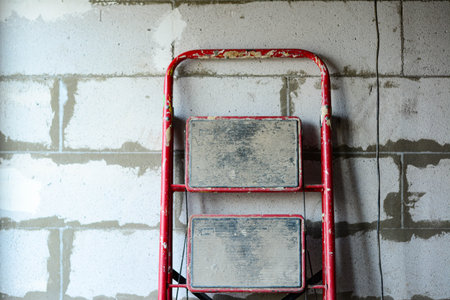 Red ladder on the background of a wall of aerated concrete blocks.