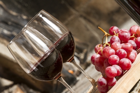 Wine cups, cork, bottle of wine, wood, grapes and fire on the background の写真素材