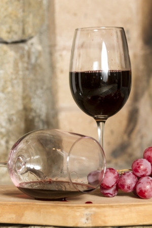 Glasses of red wine and grapes on wooden baseの写真素材