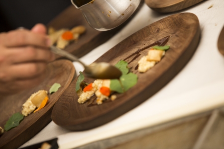 Meal in a wooden plate an people working on the preparation の写真素材
