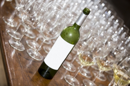 bottle of red wine empty and several wine cups on a wooden tableの写真素材