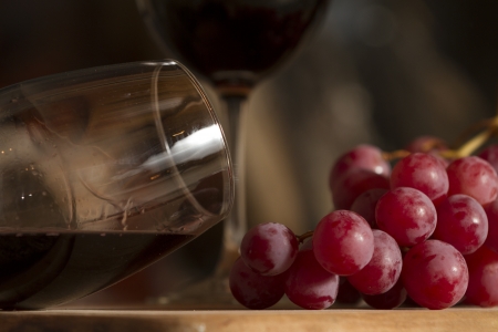 Wine glasses, Grapes, cork and a bottle of wine over a wooden table with fire on the background の写真素材