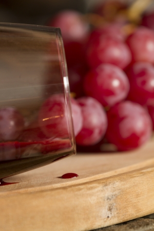Wine glasses, Grapes, cork and a bottle of wine over a wooden table with fire on the background の写真素材