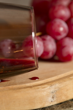 Wine glasses, Grapes, cork and a bottle of wine over a wooden table with fire on the background の写真素材
