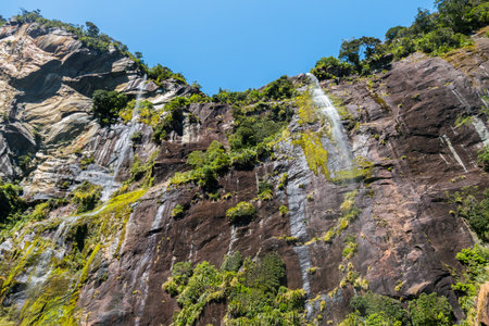 Views up right into several waterfalls falling down a steep cliff. Located right at Milford Sound this sight can only be seen by boat.の写真素材