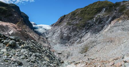 A close up image of the Franz-Josef Glacier on a sunny day. Gray gravel create the river bed for the glacier stream.の写真素材