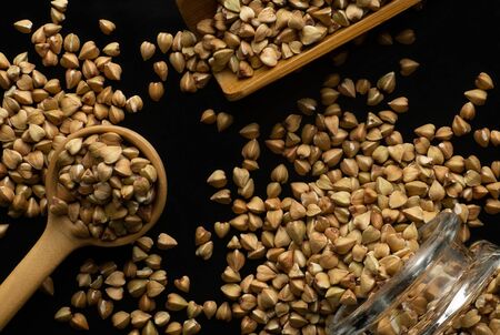 Wooden spoon, wooden scoop and glass jar with buckwheat groats close-upの写真素材