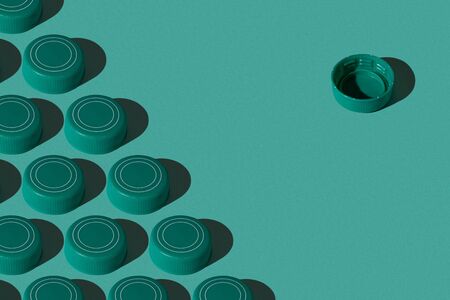 One against all. Green plastic bottle caps pattern on green background. Minimal modern concept.の写真素材
