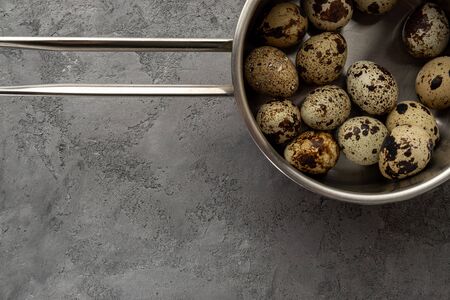 Quail eggs in a metal pan with a handle on concrete surfaceの写真素材