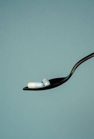 Two blue-white pills in a black metal spoonの写真素材