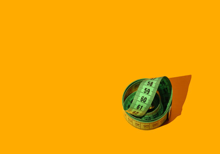 Green measuring tape on yellow background