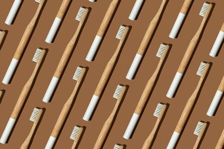 Pattern: bamboo toothbrushes with a white handle and hard shadow on brown background. Zero waste, eco lifestyle. Biodegradable material. Vertical frame.の写真素材