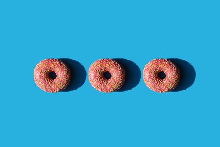 Three donuts in a row on a blue backgroundの写真素材