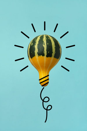 Yellow-green pumpkin in the form of a light bulb without shadow on a blue background in a wire....