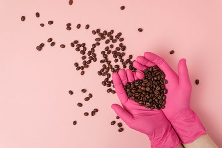 Female hands in pink medical gloves holding coffee beans