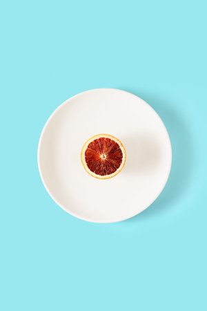 Red orange fruit on a white plate on a blue background