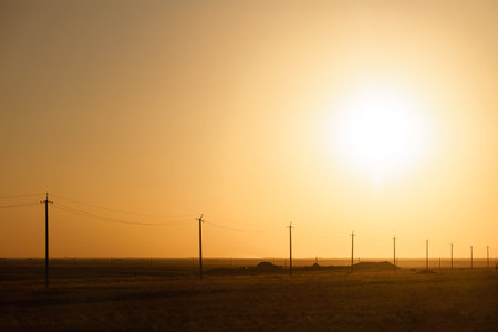 Beautiful orange sunset in the steppe. Orange smoke. Electric poles.