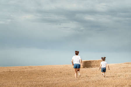 Mom and daughter run across the fieldの写真素材