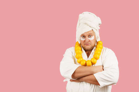 Bearded man wearing white bathrobe, towel and necklace of orangesの写真素材