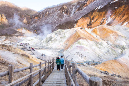 Jigokudani or Hell Valley in the town of Noboribetsu Onsen Hokkaido, Japan, hot steam vents, sulfurous streams. The couple is sightseeing on the wooden bridge which shown a romantic moment.のeditorial素材