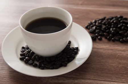 black coffee in white cup and coffee bean on wooden tableの写真素材