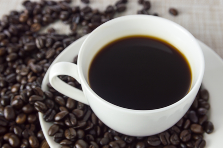 black coffee in a white cup and coffee beans on naperyの写真素材