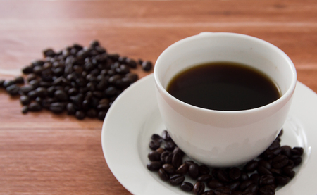black coffee in white cup and coffee bean on wooden tableの写真素材