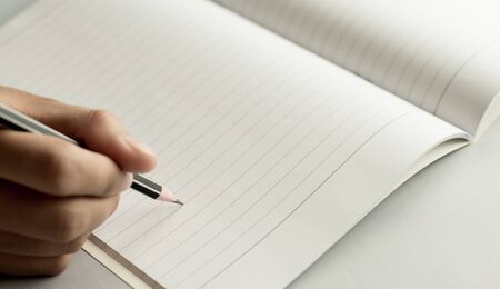 young women writing on blank notebook by black pencilの写真素材
