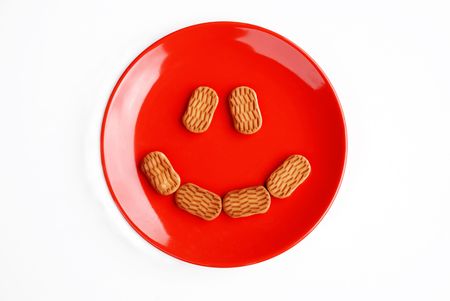Red plate with cake eyes and mouth isolated over whiteの写真素材